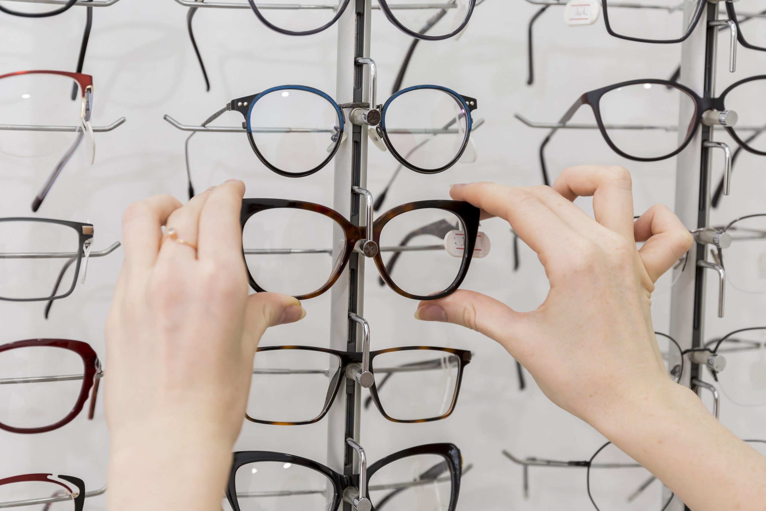 Person grabbing eyeglasses from an optical display