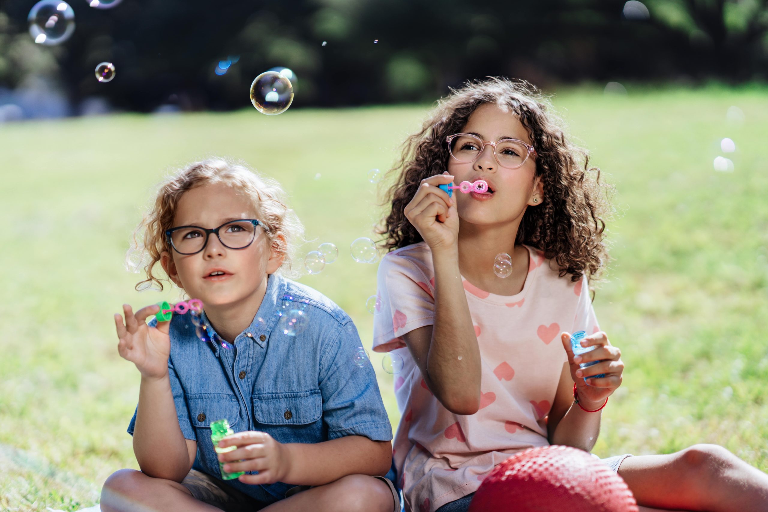 Children blowing bubbles while wearing eyeglasses from A&A Optical