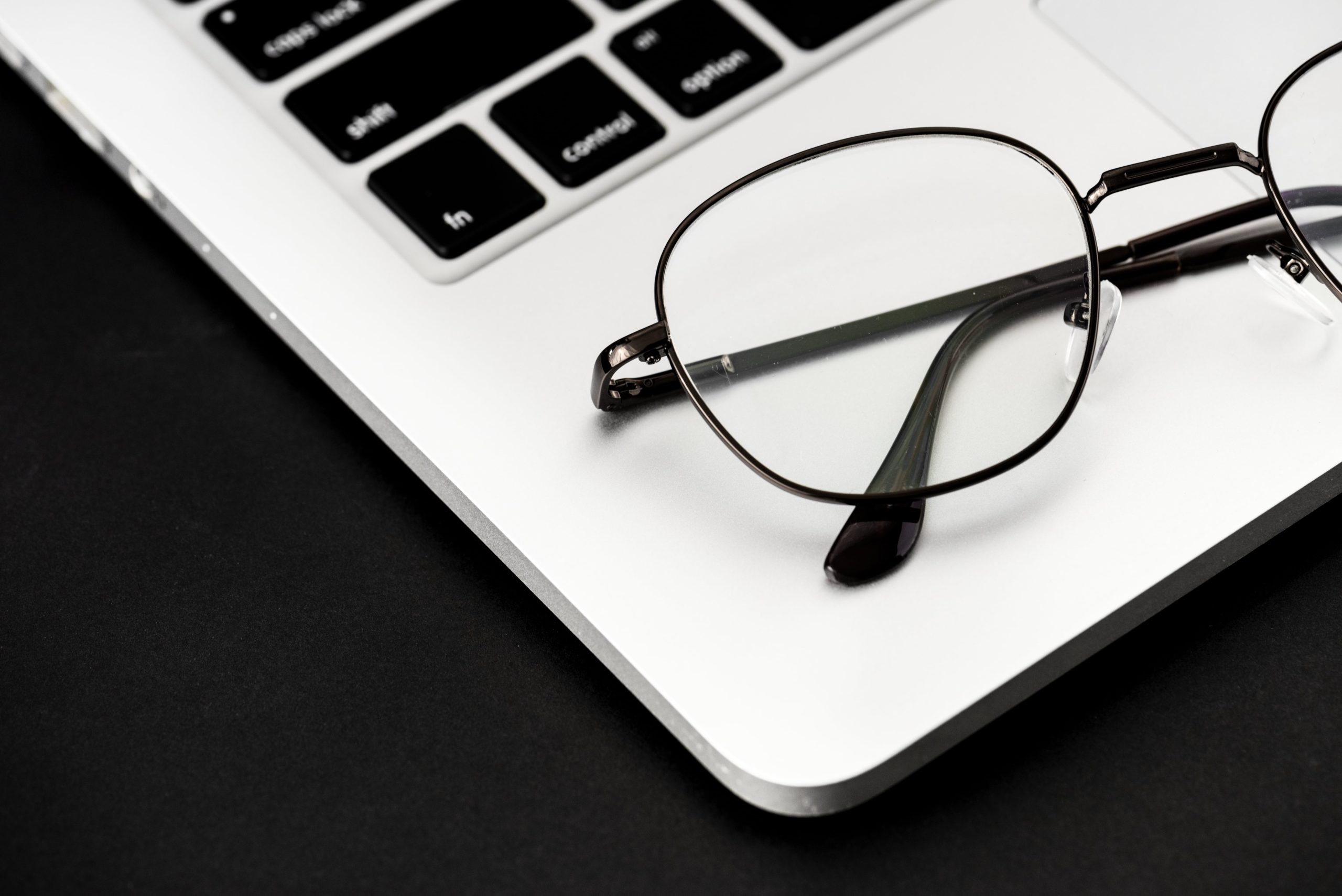 Eyeglasses resting on the surface of a Macbook